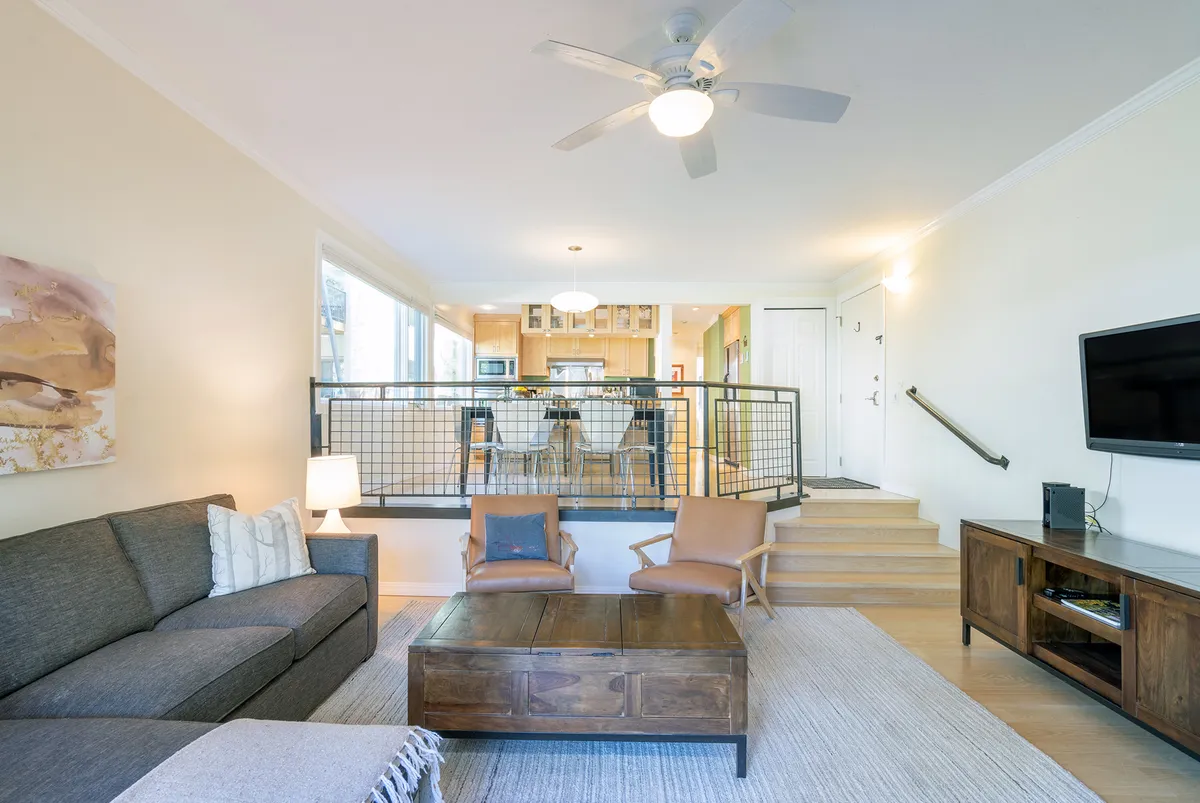 A cozy, open-plan living area featuring a plush sofa, coffee table, TV stand, and adjacent dining area. The arrangement encourages relaxation and socialization, with warm tones and soft lighting creating a welcoming atmosphere. The space is perfect for gatherings, movie nights, or simply unwinding after a day outdoors.