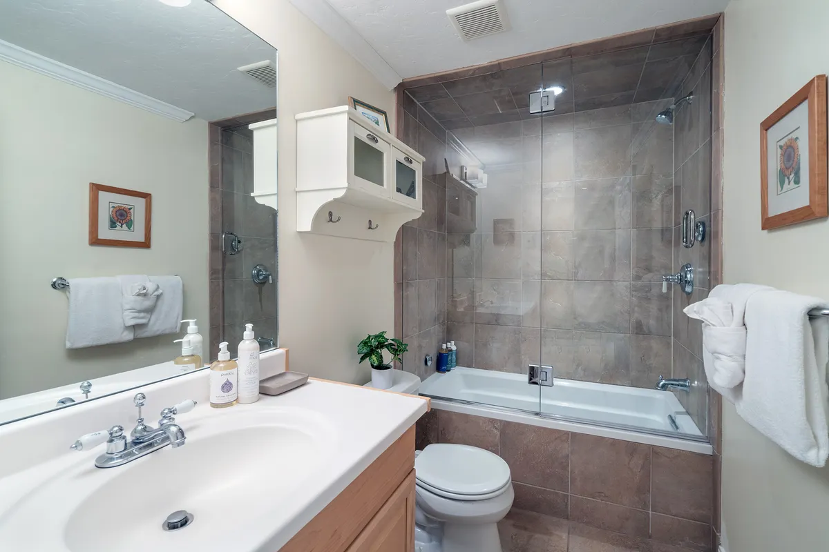 A well-organized full bathroom with a vanity sink, shower area, and toilet. Decorative wall art adds warmth, and the space is designed for both relaxation and convenience.